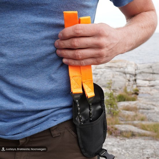 Man houdt oranje riemen vast met zwart opbergzakje buiten bij rotsachtig landschap