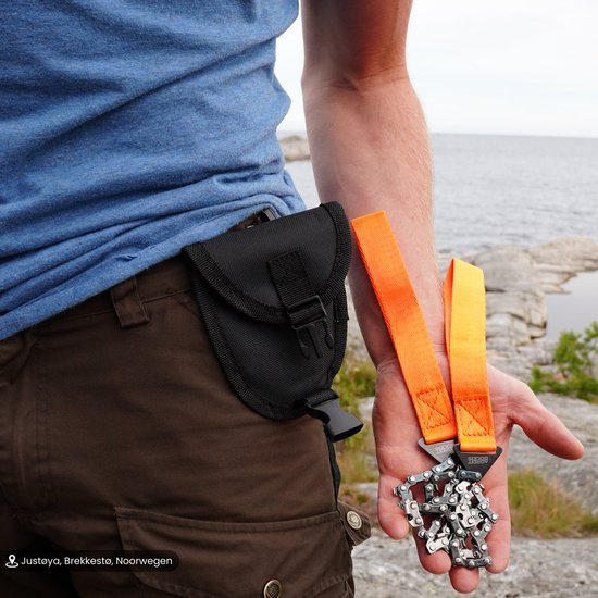 Mannelijke hand houdt oranje ketting met slot, zwarte heuptas bevestigd aan bruine broek bij waterkant