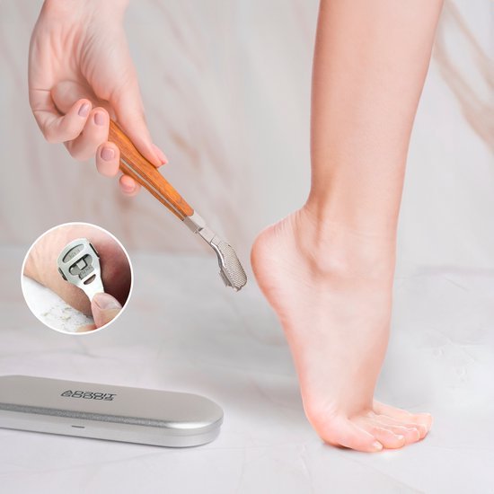 Hand die voet verzorgingsgereedschap met houten handvat en roestvrijstalen metalen kop vasthoudt