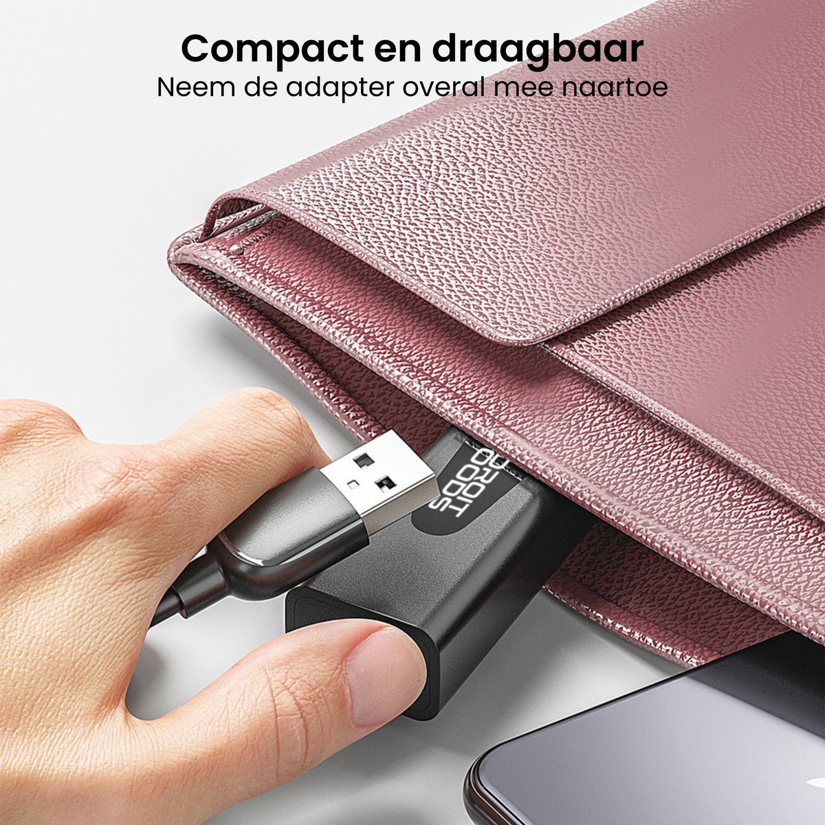 Hand steekt compacte zwarte adapter met USB-kabel in roze kleine draagtas naast smartphone