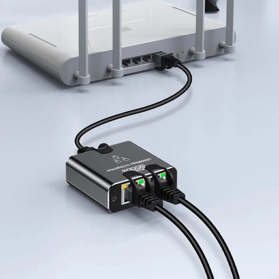 Zwarte netwerkverdeler aangesloten op een witte router met drie netwerkkabels aangesloten.