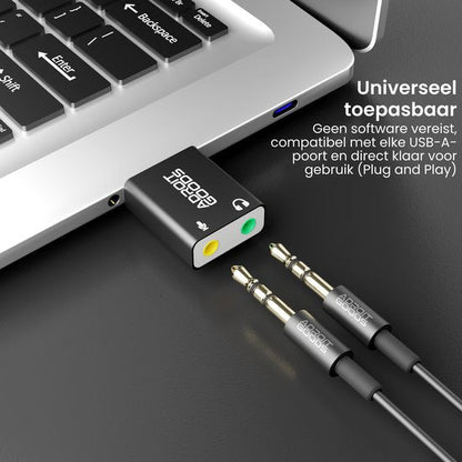 USB-geluidskaart adapter aangesloten op laptop met twee audiokabels op zwarte ondergrond