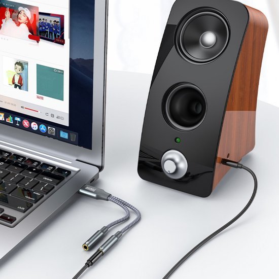 Laptop verbonden met een houten speaker en een adapterkabel voor audio-uitbreiding.