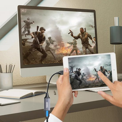 Hand die tablet aan een computer koppelt met een kabel terwijl een actiespel wordt gespeeld