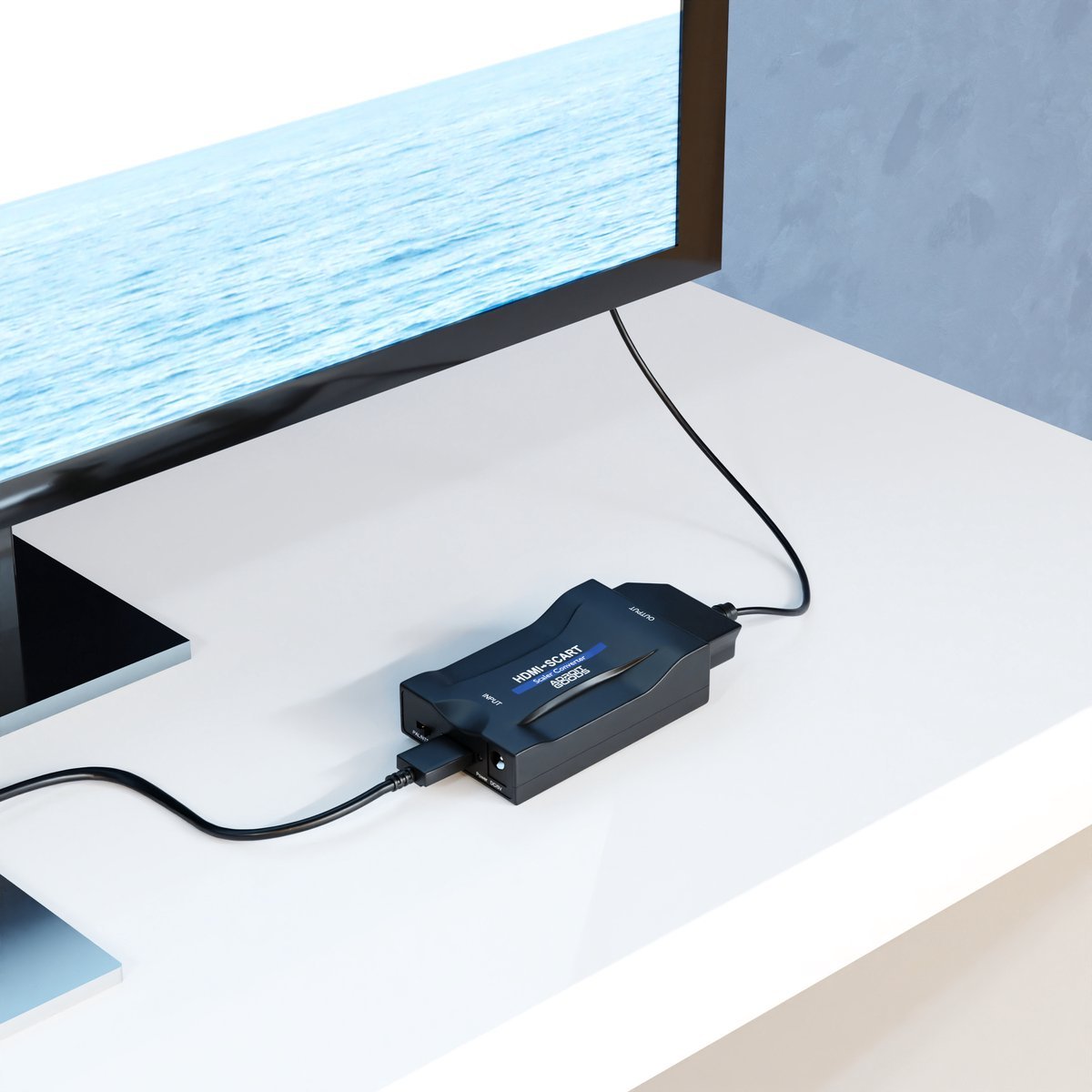 Zwart elektronisch apparaat verbonden met een televisie op een witte tafel in een lichte kamer.