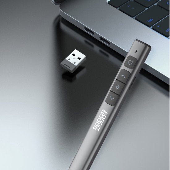draadloze presenter met knoppen en usb-ontvanger naast laptop op zwarte tafel