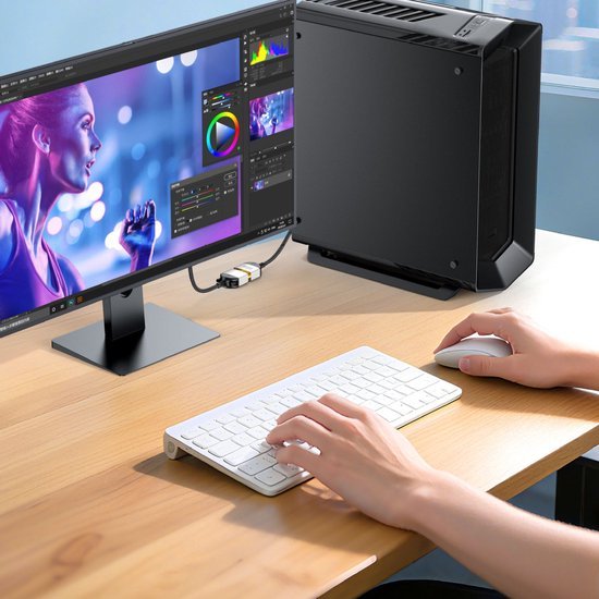 Handen gebruiken draadloos wit toetsenbord en muis bij desktopcomputer met kleurrijk scherm