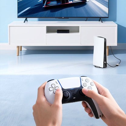 Iemand die met een wit en zwart spelcontroller op een bank videogames speelt met tv op de achtergrond