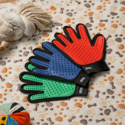 Drie zachte verzorghandschoenen in rood, blauw en groen met zachte nopjes, op een dierenprintdeken.