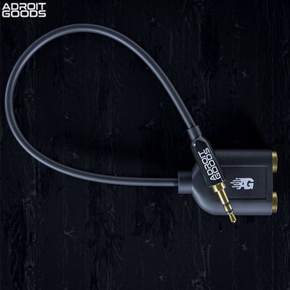 Zwarte audio splitter met goudkleurige connectoren en kabel op een zwarte achtergrond.