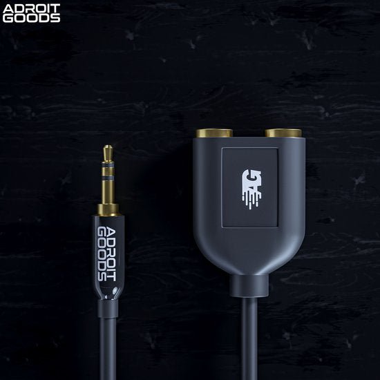 Zwarte audio splitter met AdroitGoods logo en twee vrouwelijke aansluitingen op zwarte achtergrond