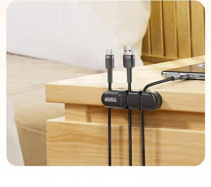 Zwart kabelbeheer met AdroitGoods logo, bevestigd aan houten meubel, met USB-kabels georganiseerd.