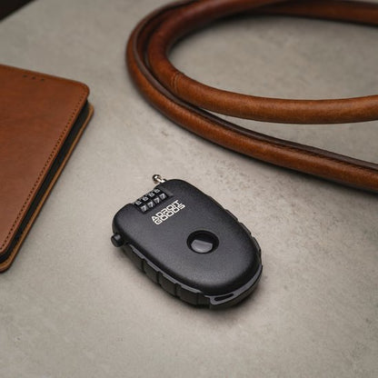 zwart compact cijferslot met draaiknop naast bruine leren riem en notitieboekje