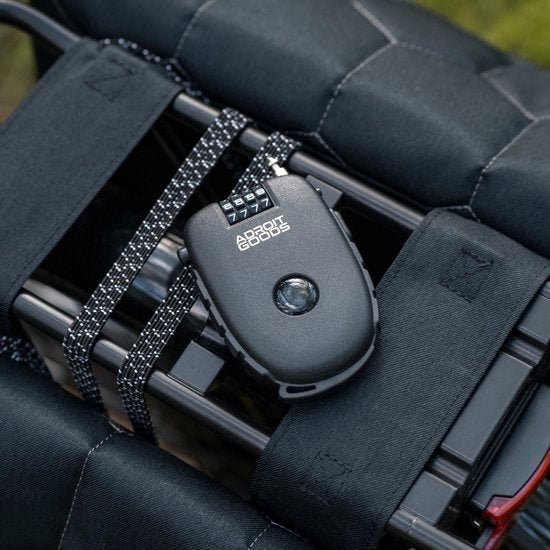 Zwart slim cijferslot met reflecterend touw bevestigd aan bagagerek met zwarte riemen
