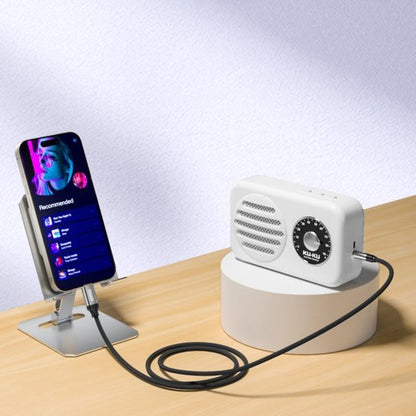 Witte retro radio verbonden met smartphone via kabel op houten tafel met standaard