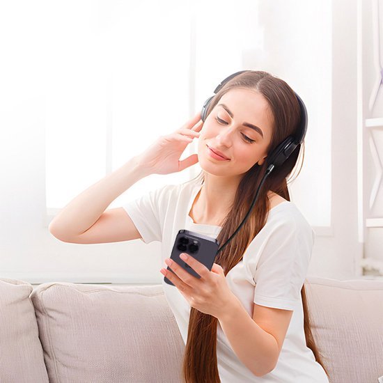 Vrouw met lange haren die ontspannen muziek luistert via een hoofdtelefoon en smartphone houdt.