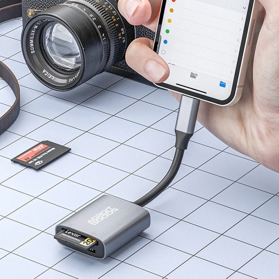 Hand die smartphone met adapter verbindt met geheugenkaarten en camera op wit roosteroppervlak