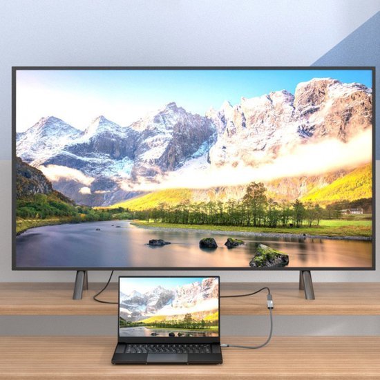 Laptop verbonden met een groot scherm toont een berglandschap met rivier en zonnige horizon