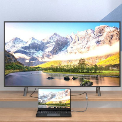 Laptop verbonden met een groot scherm toont een berglandschap met rivier en zonnige horizon