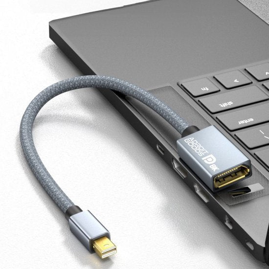 grijze kabeladapter met geweven hoes aangesloten op laptop met meerdere poorten