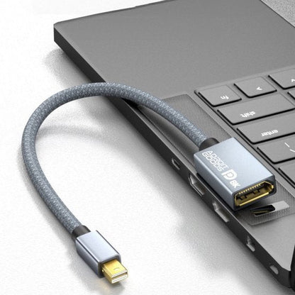 grijze kabeladapter met geweven hoes aangesloten op laptop met meerdere poorten