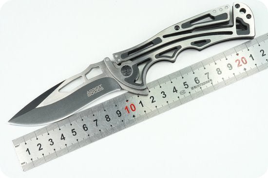 vouwmes met metalen handgreep en open lemmet naast een meetlat op wit oppervlak