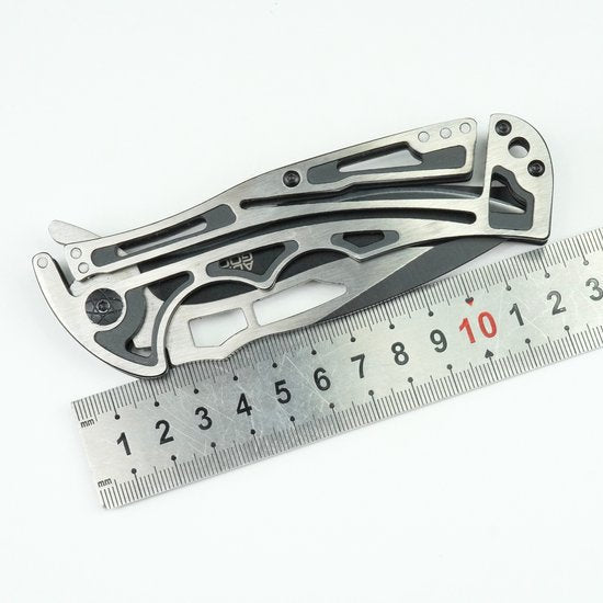 Vouwmes van roestvrij staal met geperforeerd handvat naast een metalen liniaal van 15 cm