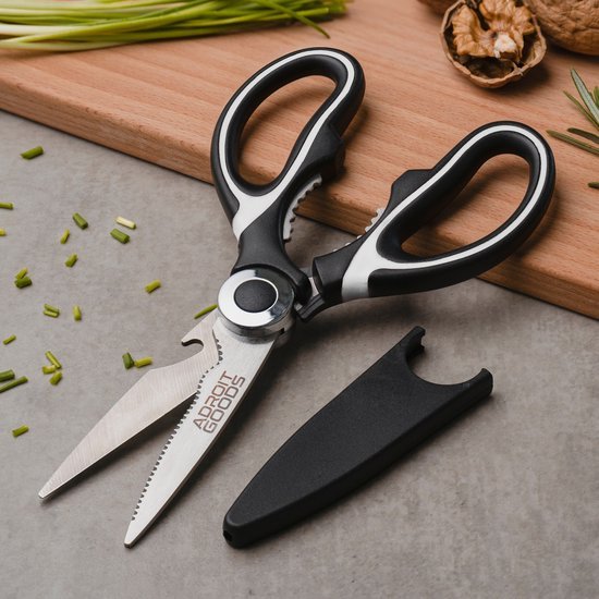 Keukenschaar met zwarte handgrepen en extra beschermkap op grijze ondergrond naast noten en bieslook