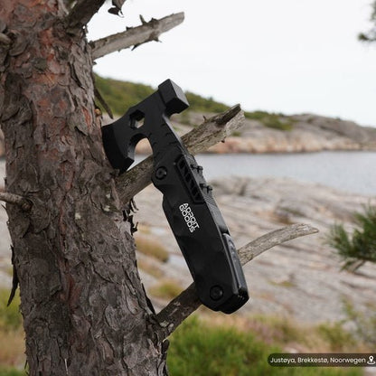 Zwart multitool bij een boom vastgemaakt in een buitenomgeving met rotsen en water op de achtergrond