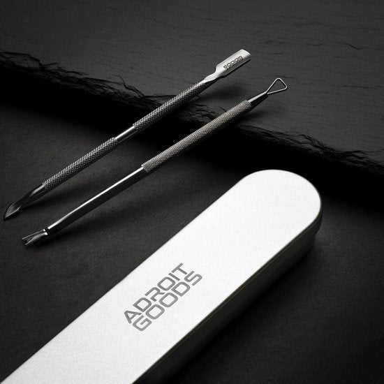 Twee roestvrijstalen gereedschappen naast een metalen etui op een donkere achtergrond