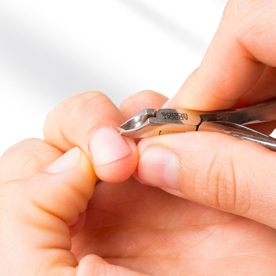 Hand knipt voorzichtig nagelriemen met een roestvrijstalen nagelknipper.