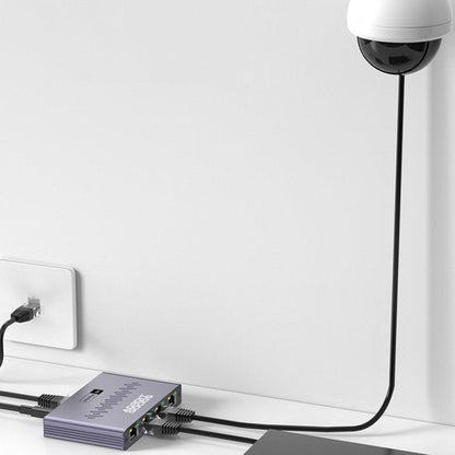 Beveiligingscamera aangesloten op een netwerkadapter met meerdere kabels tegen een witte muur