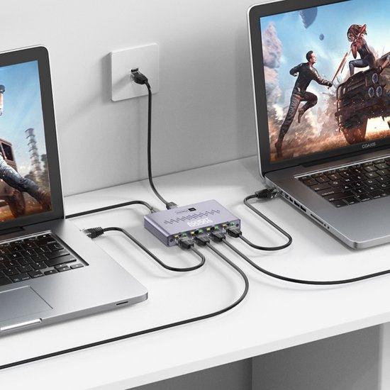 Twee laptops verbonden met een centraal apparaat via meerdere USB-kabels op een bureau.