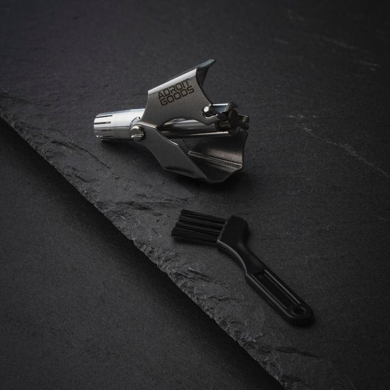 Roestvrijstalen metalen gereedschap met borsteltje op zwarte steenachtige ondergrond