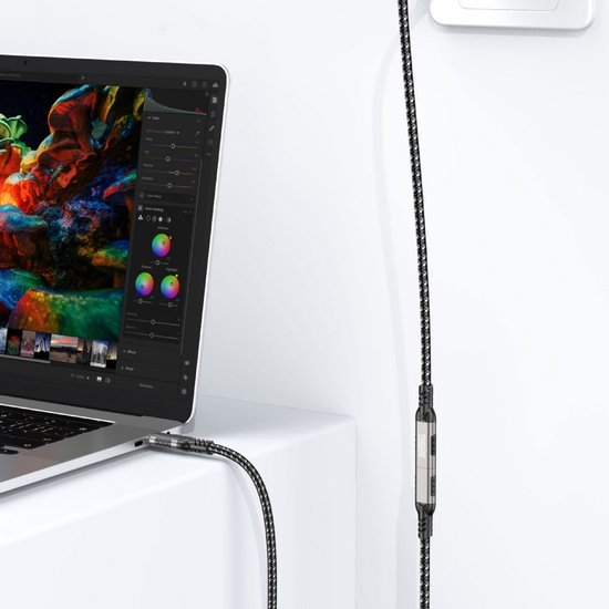 Zwart-witte gevlochten oplaadkabel aangesloten op een laptop en een wandstekker.