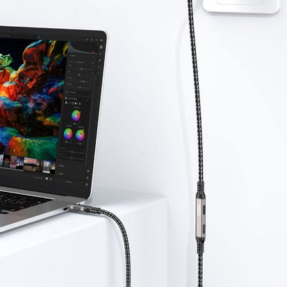 Zwart-witte gevlochten oplaadkabel aangesloten op een laptop en een wandstekker.