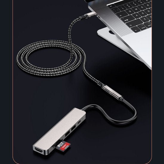 zilvergrijze usb-c hub aangesloten op laptop met sd-kaart en gevlochten kabel