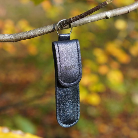 Zwarte leren sleutelhanger met metalen ring hangend aan een tak in de natuur