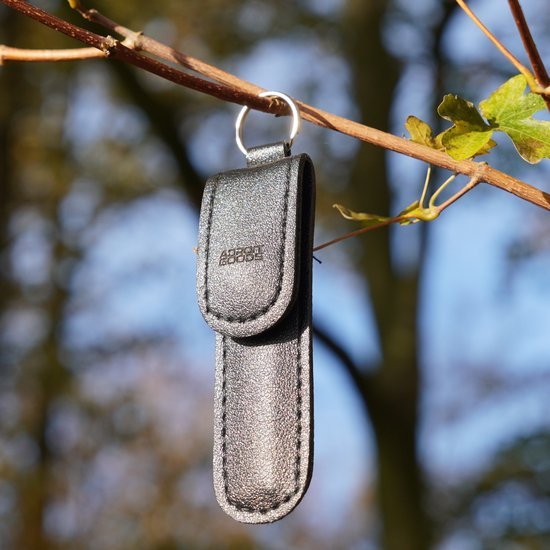 zwarte leren sleutelhanger met metalen ring hangend aan tak buiten in natuurlijk licht