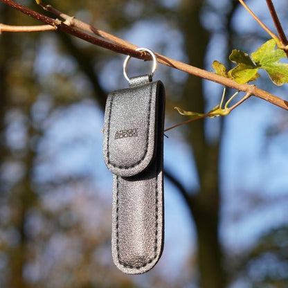 zwarte leren sleutelhanger met metalen ring hangend aan tak buiten in natuurlijk licht
