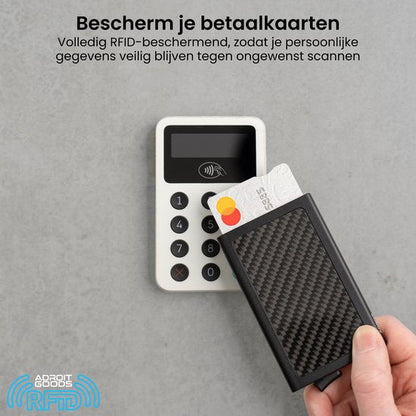 Hand die een zwarte RFID-beschermhoes vasthoudt met een creditcard bij een betaalterminal