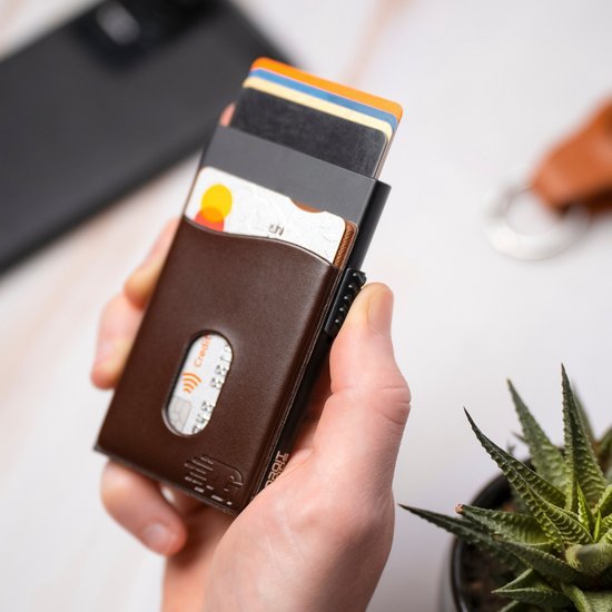 Hand die een slanke leren portemonnee met meerdere kaarten en een zwarte smartphone vasthoudt.