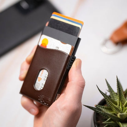 Hand die een slanke leren portemonnee met meerdere kaarten en een zwarte smartphone vasthoudt.