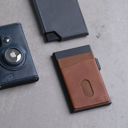 Drie verschillende compacte portemonnees van leer en kunststof op een grijze ondergrond.