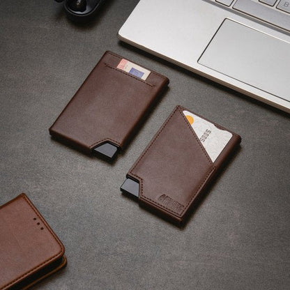 Twee stijlvolle bruine leren kaarthouders naast een laptop op een donker bureau gelegen.