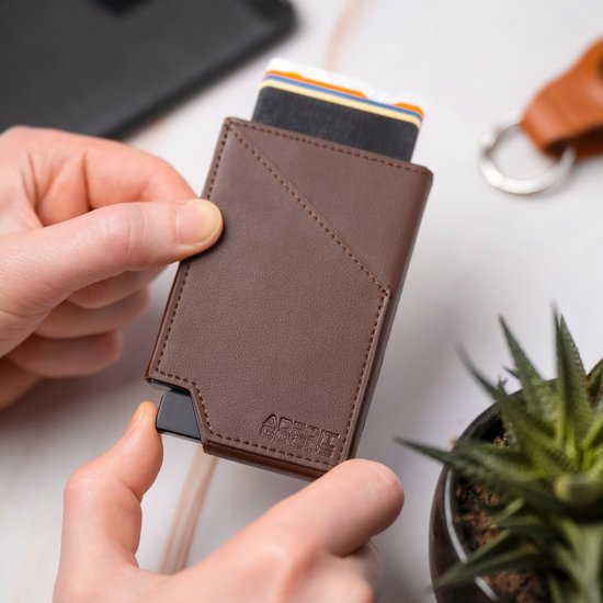 Hand die een bruin leren kaarthouder vasthoudt met meerdere pasjes erin gestoken