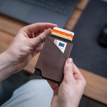 Twee handen houden een bruin leren portemonnee met meerdere passen en kaarten zichtbaar