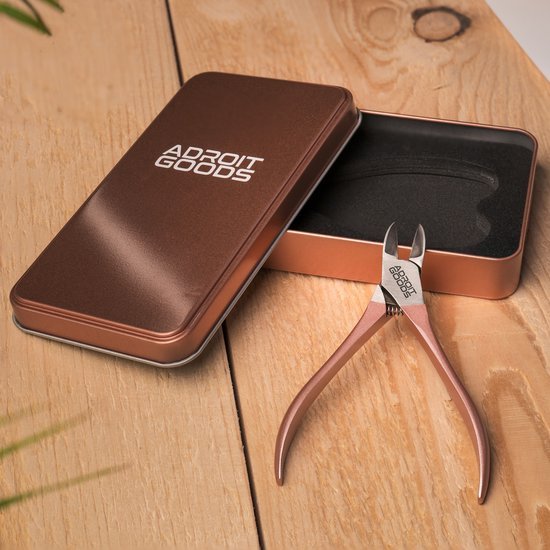 Roestvrijstalen nagelknipper met ergonomisch design en metalen opbergdoosje op houten tafel.