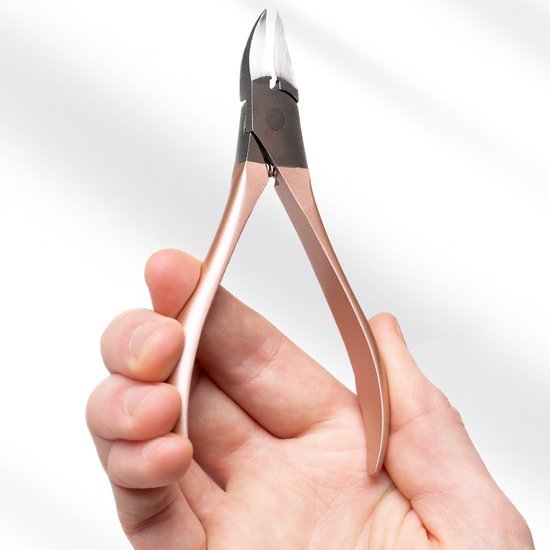 Hand die een metalen nagelkniptang met roségouden handvat vasthoudt tegen een witte achtergrond