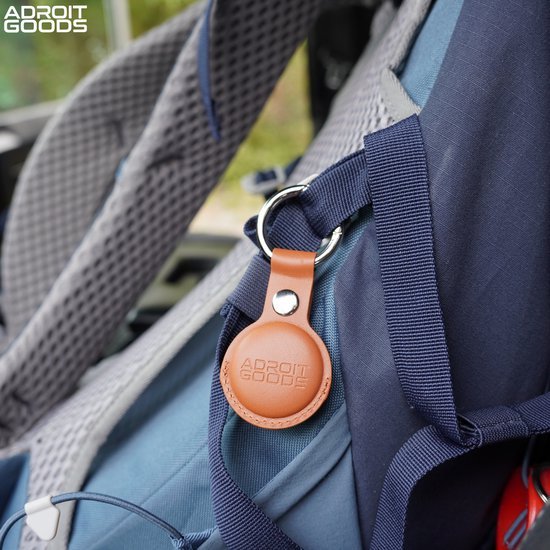 leren sleutelhouder met AdroitGoods logo aan blauwe rugzak bevestigd in buitenomgeving